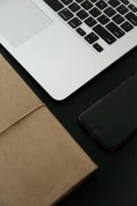 Brown Leather Journal beside a Gray Laptop